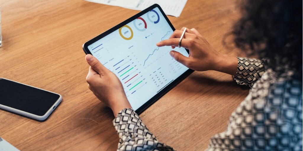 Close up of a woman doing financial analysis at work on a tablet at her desk.