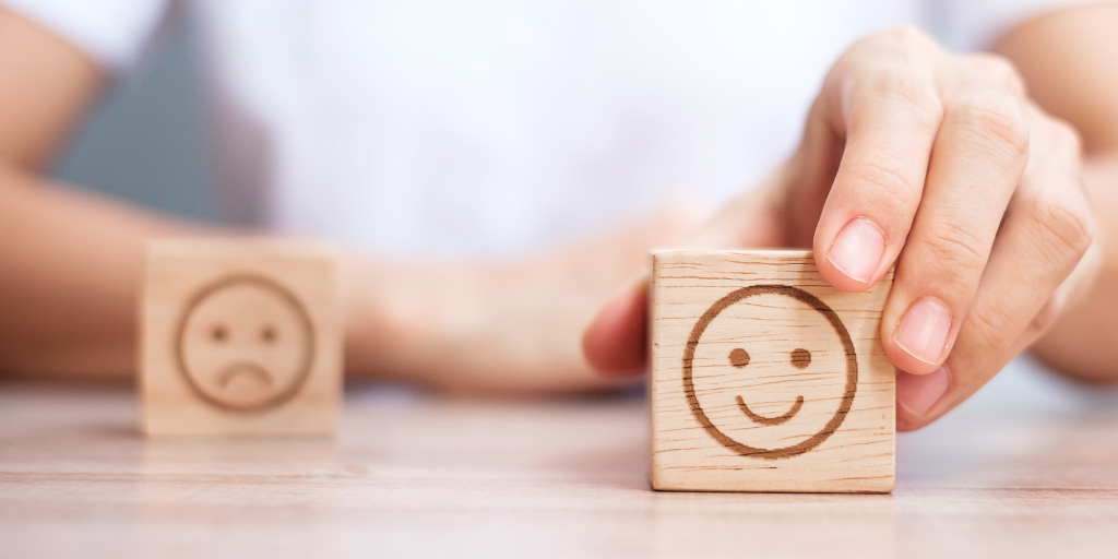 Dos bloques de madera con uno que tiene una cara sonriente en el frente y el siguiente bloque con una cara triste.