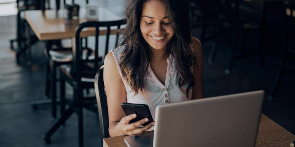 mujer en el iphone con el portátil